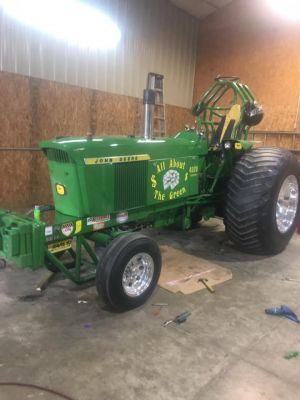 green pulling tractor parked inside a garage