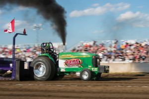 Green tractor tractor pulling with black smoke coming out the top