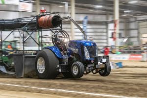 blue tractor at an indoor tractor pulling event