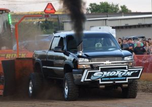 black pulling truck blowing black smoke at truck pulling event