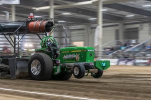 green tractor pulling inside