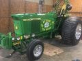 green pulling tractor parked inside a garage