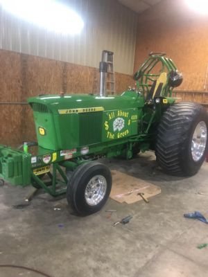 green pulling tractor parked inside a garage green pulling tractor parked inside a garage