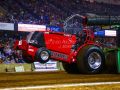 bright red tractor pulling inside with the front wheels coming off the ground