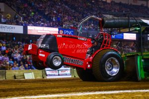 bright red tractor pulling inside with the front wheels coming off the ground