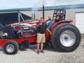 man standing in front of his red pulling tractor