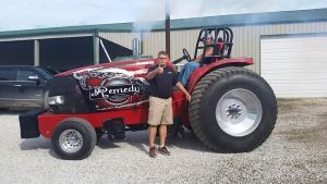 man standing in front of his red pulling tractor