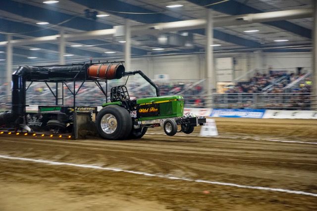 indoor tractor pulling event featuring a green tractor indoor tractor pulling event featuring a green tractor
