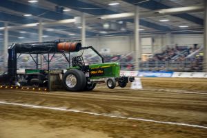 indoor tractor pulling event featuring a green tractor