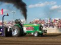 Green tractor tractor pulling with black smoke coming out the top