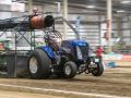 blue tractor at an indoor tractor pulling event
