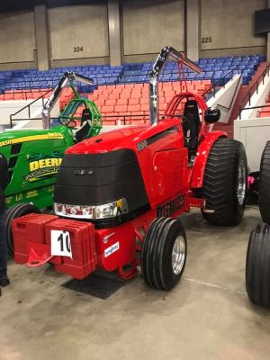 Red shiny pulling tractor parked inside